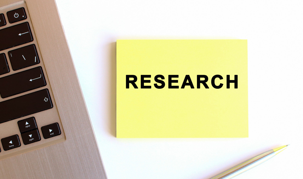 Photo of laptop with yellow sticky note with the word "research" on it.